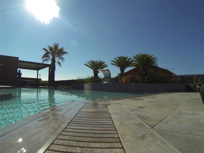 piscina bordo sfioro con griglia in pietra